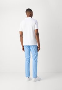 Hvid polo-shirt, blå bukser og hvide sneakers. Outfittet har et klassisk design med korte ærmer og en simpel krave.