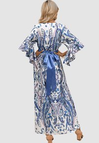 Vestido largo y fluido con un patrón de paisley en azul y rosa sobre un fondo blanco. Tiene mangas con volantes y un lazo de satén en la cintura.