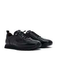 Zapatillas de cuero negro con textura suave, punta redonda, diseño con cordones y suela de goma con un patrón texturizado.