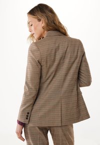 Brun rutigt kavaj med en notch-lapel, skräddarsydd passform, texturerad tyg och detaljer med tre knappar vid ärmarna. Lämplig för formella sammanhang.