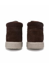 Bottines en daim marron avec des arrières arrondis, des semelles en caoutchouc texturé et une doublure orange contrastante visible au niveau de l'ouverture supérieure.