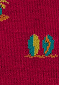 Tessuto rosso con alberi ricamati colorati in verde, giallo e arancione. La trama è leggermente ruvida, con un motivo tessuto.