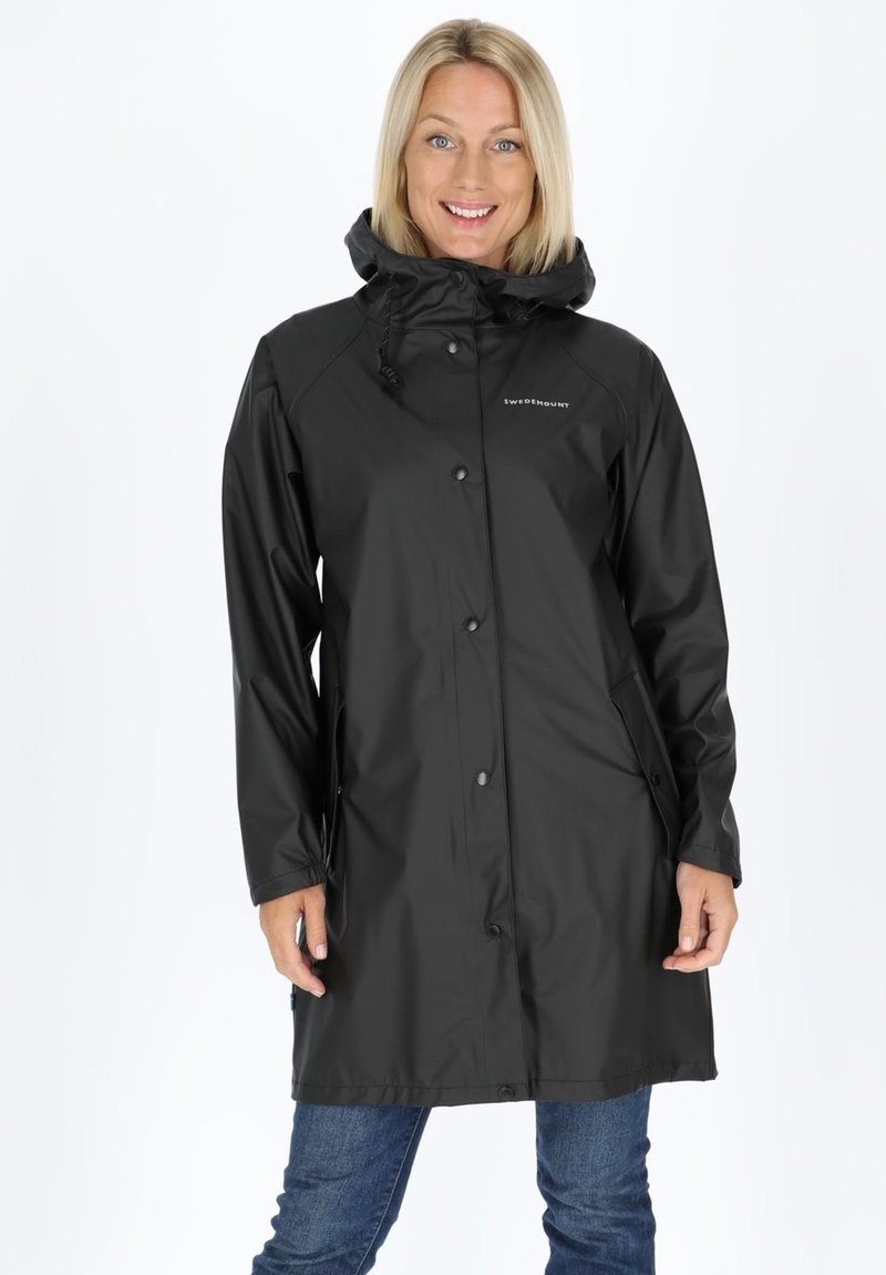 Black waterproof raincoat with a hood, snap buttons, two side pockets, and adjustable hem, displayed on a person against a white background.