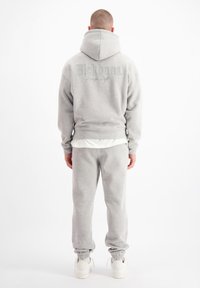 Grijze hoodie met groot logo op de achterkant, gecombineerd met bijpassende sweats. Zachte stof, comfortabele pasvorm, ribgebreide manchetten en elastische tailleband.