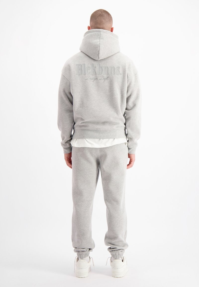 Grijze hoodie met groot logo op de achterkant, gecombineerd met bijpassende sweats. Zachte stof, comfortabele pasvorm, ribgebreide manchetten en elastische tailleband.