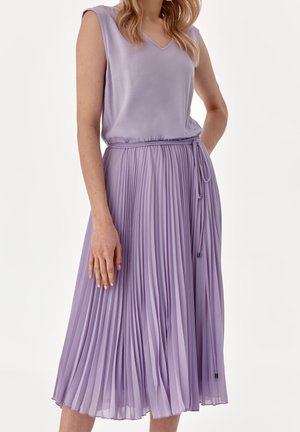 Ärmelloses lavendelfarbenes Kleid mit V-Ausschnitt und plissiertem Midirock, mit dünnem Taillengürtel vor neutralem Hintergrund.