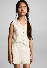 Completo due pezzi beige chiaro composto da un top senza maniche con ricami e tre bottoni dorati, abbinato a pantaloni corti coordinati con bordi a scallop.