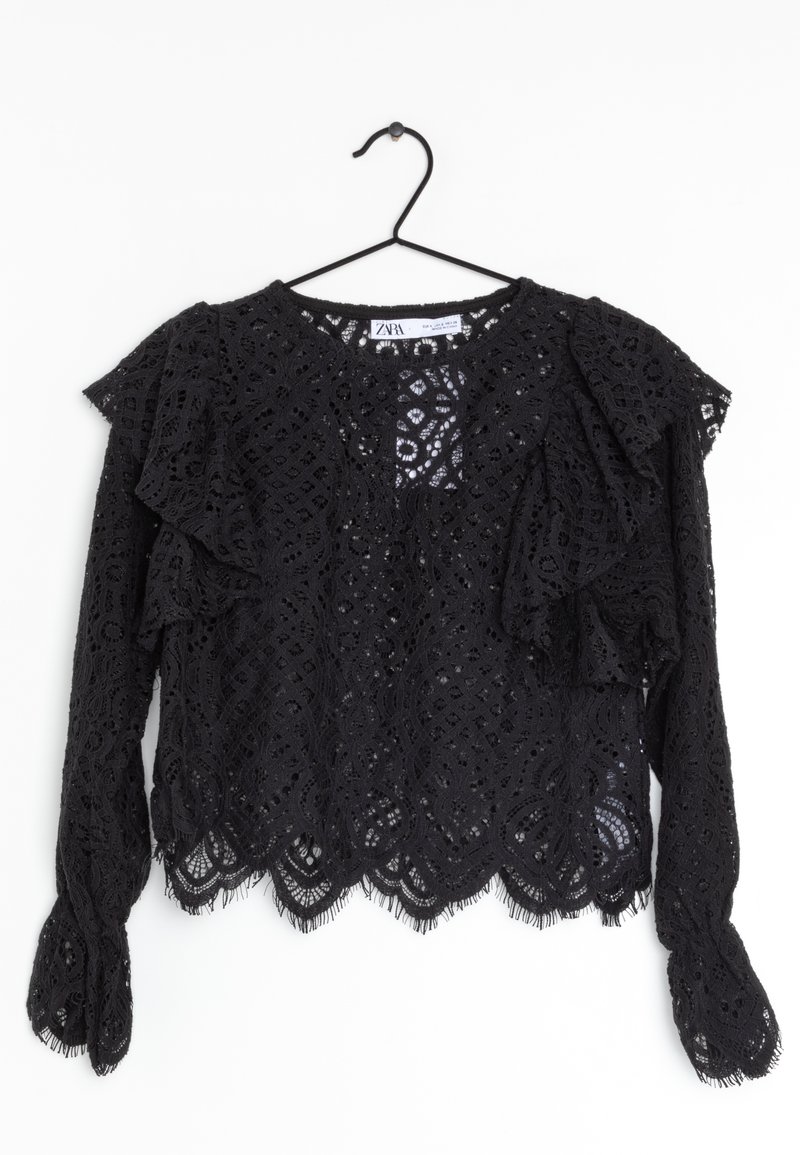 Haut en dentelle noire avec des manches à volants, arborant un ourlet festonné et un motif géométrique complexe. Texture douce et design ouvert dans l'ensemble.