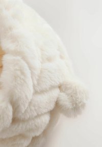 Sanfter, flauschiger Wurfdecke in Off-White, mit einer plüschigen Textur und einem gesteppten Design mit abgerundeten Ecken.