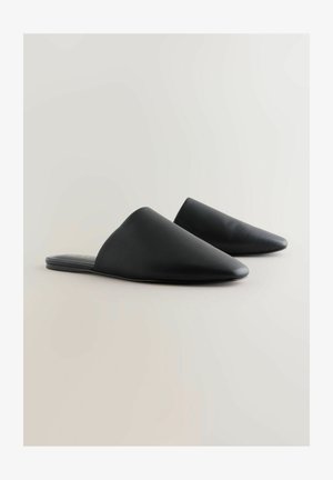 Juodos smailianos nosies mules, su lygiu odiniu viršumi, lengvai užsidėjamomis, plokščiu padu ir švariu, minimalistiniu estetiniu stiliumi.