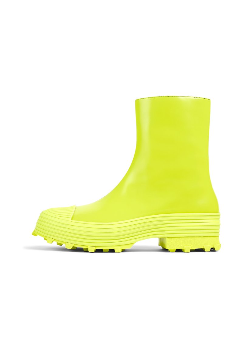 Neon yellow rubber ankle boot with a ridged sole, rounded toe, and textured accents. Smooth finish with a glossy appearance.