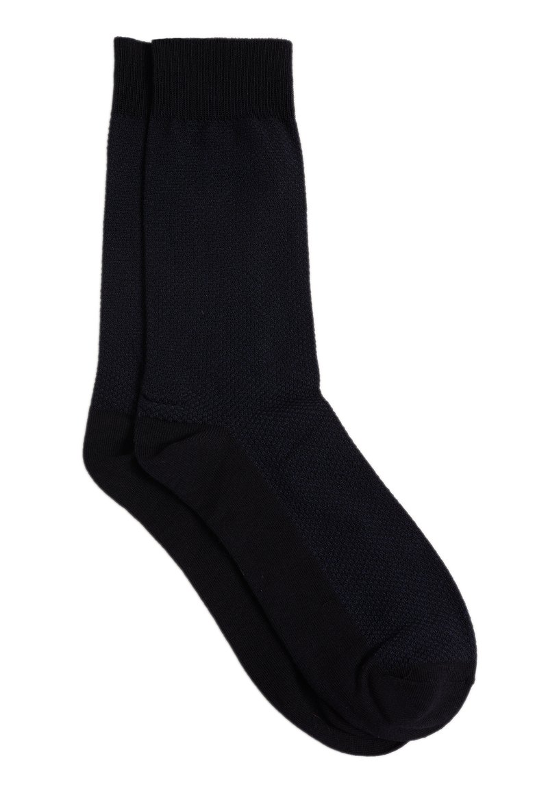 Svarta strumpor med ribbat manschett, strukturerat kropp och slät fotdel. Materialet verkar mjukt, utan synliga mönster eller detaljer.