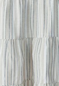 Gestreepte stof met smalle marineblauwe en witte strepen op een lichtbeige achtergrond, met een textuur en een geplooid ontwerp bij de zoom.