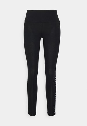 Black leggings with a high waist, made of smooth fabric. Features a printed brand logo on the side. Designed for comfort and flexibility.