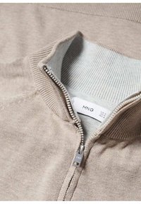 Maglione beige con zip, colletto e polsini a coste, dotato di una zip argentata e texture morbida. Etichetta di cura visibile all'interno.