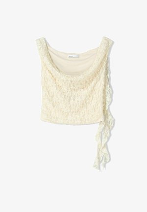 Spetscroppad topp i off-white, med en mjuk drapering, rundad halsringning och en sidoknytning för justerbar passform. Delikat blommönster över hela.