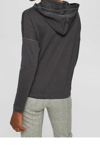 Felpa con cappuccio grigia scura a maniche lunghe, con una texture morbida e dettagli di cucitura a contrasto, abbinata a pantaloni grigi chiari texturizzati.