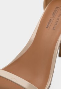 Κοντινό πλάνο μπεζ vegan γυναικείου παπουτσιού με ψηλό τακούνι, λεπτό λουρί και εσωτερική σόλα με την επωνυμία "Coolway Vegan".