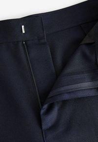 Pantaloni negri închisi, ajustați, cu închidere cu fermoar, țesătură cu un ușor luciu și un detaliu mic din metal sub formă de cârlig la talie.