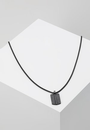 Collier en métal noir avec un pendentif rectangulaire texturé, présentant une bande centrale et une chaîne tissée. Design minimaliste sur un fond neutre.