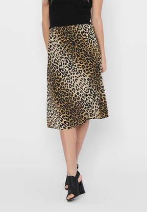 Midi spódnica w panterkę o zwiewnym fasonie, z czarnym, elastycznym pasem i gładką fakturą. Zestawiona z czarnymi, otwartymi na palce szpilkami.