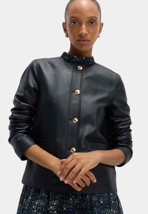 Veste en cuir noir avec un col rond, ornée de boutons dorés, de poches latérales et d'une accent floral texturé au niveau du col.