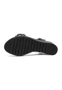 Sole di sandalo nera con texture in gomma rigata, scanalature pronunciate per la presa e piattaforma del tallone strutturata con una leggera outline grigia.