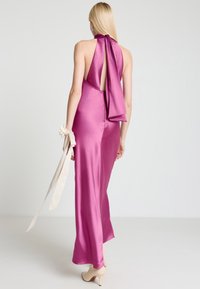 Fuchsiafarbener Satinballkleid mit offenem Rücken und großer Schleifendetail am Hals. Es hat eine gerade Silhouette und ein cremefarbenes Handgelenk-Akzent mit Bändern.