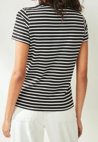 Czarna i biała koszulka w paski z krótkimi rękawami i okrągłym dekoltem, wykonana z miękkiego materiału. Zaprojektowana z luźnym krojem, bez widocznych elementów metalowych.