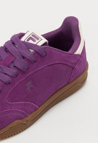 Lilla semsket sneakers med brun gummisåle, med snørebånd, polstret krage og logo på tunge. Glatt tekstur og buet design.