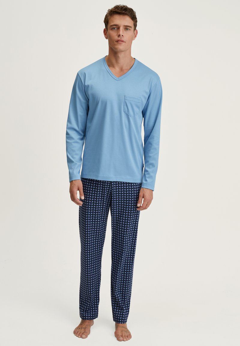 Un haut bleu clair à manches longues et col en V avec une poche sur la poitrine, associé à un pantalon de pyjama marine à motif à carreaux.