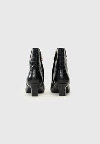 Bottes de cheville noires à talons avec une texture crocodile, des accents en métal doré et un design de talon carré compact.