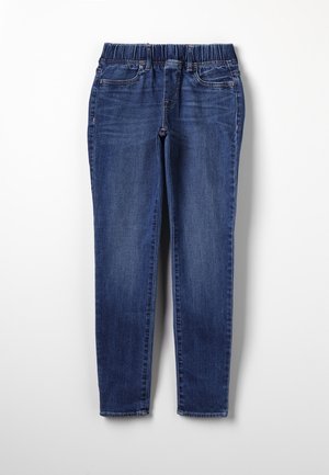 Jean en denim bleu avec taille élastique, poches avant et jambes droites et étroites, étalé à plat sur un fond blanc.