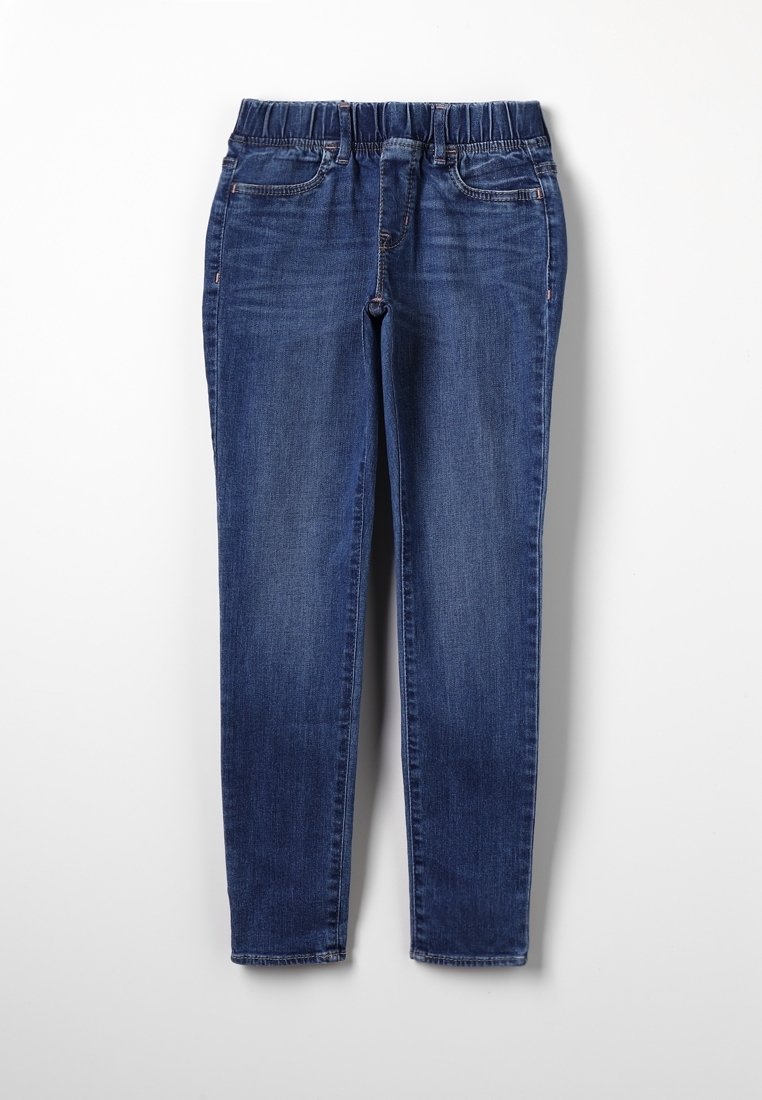 Jean en denim bleu avec taille élastique, poches avant et jambes droites et étroites, étalé à plat sur un fond blanc.