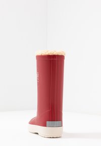 Botte en caoutchouc rouge avec une doublure en faux cuir beige et douce en haut, semelle blanche texturée et un accent gris au niveau du talon.