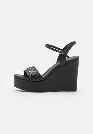 Sorte kilehøjhælede sandaler med bred rem og logodetalje, med justerbar ankelrem og glat mat finish.