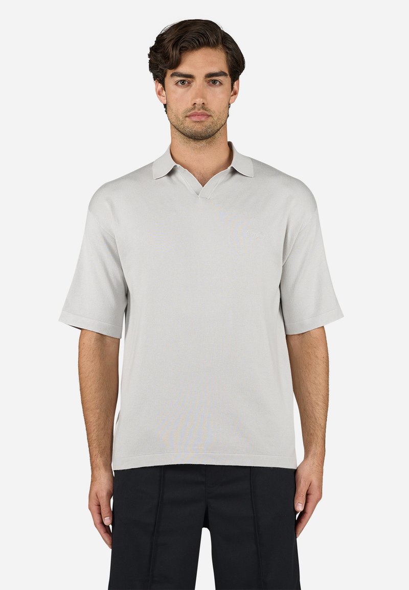 Polo de manga curta cinza claro com decote em V, textura suave e detalhe de logótipo subtil. Barra reta e ajuste descontraído.