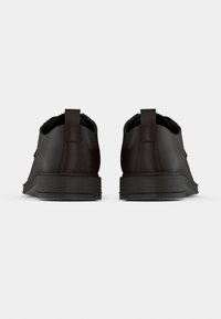 Μαύρα δερμάτινα παπούτσια με υφή, επίπεδες λαστιχένιες σόλες και θηλιά στο πίσω μέρος. Διαθέτουν μινιμαλιστικό σχεδιασμό και στρογγυλεμένο σχήμα.