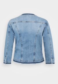 Ljusblå denimjacka med klassisk passform, med fransar i fåll, strukturerade sömmar och långa ärmar. Bakifrån visar den enkelhet i designen.