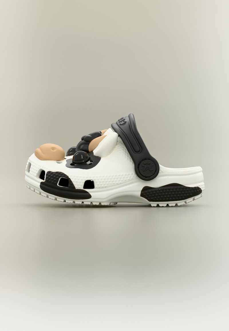 Λευκό κλογκ με μαύρο λουράκι και υφασμένα μαύρα στοιχεία, με τρισδιάστατο σχέδιο αγελάδας στο επάνω μέρος.