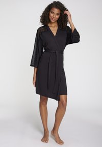 Must must robe, mis pehmeast kangast, millel on pitsist detailid käistel, ise sidumisalus ja põlve pikkune hem. Sile tekstuur.