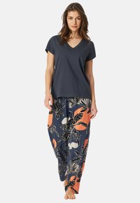 Navy v-neck t-shirt paired with loose-fitting pants featuring a bold floral pattern in coral, white, and black on a dark background.
