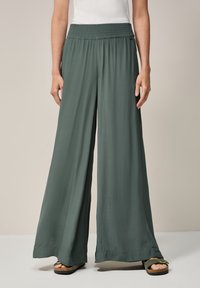 Wide-leg, green-hued pants made of lightweight fabric with a gathered elastic waistband. Features a smooth texture and long, flowing design.