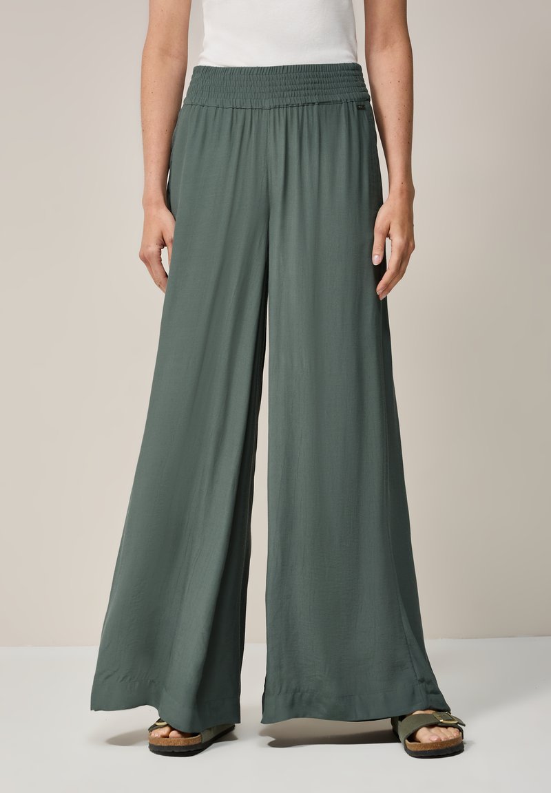 Wide-leg, green-hued pants made of lightweight fabric with a gathered elastic waistband. Features a smooth texture and long, flowing design.