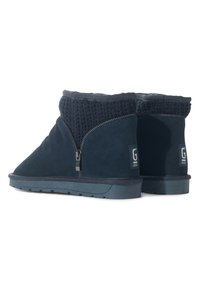 Botines azul marino con cuerpo de ante, cuello de punto, cremallera lateral y suela de goma texturizada; etiqueta con "G" en la parte posterior.
