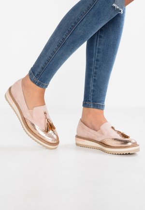 Lyserøde slip-on sko med metalkobberfarvet tå, pyntet med dekorative kvaster og tekstureret sål. Diskrete perforeringer på overdelen.