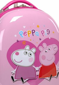 Roze harde koffer met Peppa Pig-personages, glanzende afwerking, hartaccenten en kleurrijke tekst. Ritsluiting en handvat aan de bovenkant.