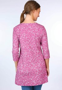 Long-sleeve tunic in pink fabric featuring a floral pattern. Back view shows round neckline and mid-thigh length. Soft texture with relaxed fit.