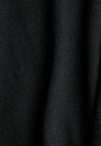 Gros plan sur un tissu noir tricoté montrant sa texture douce et son tissage fin.