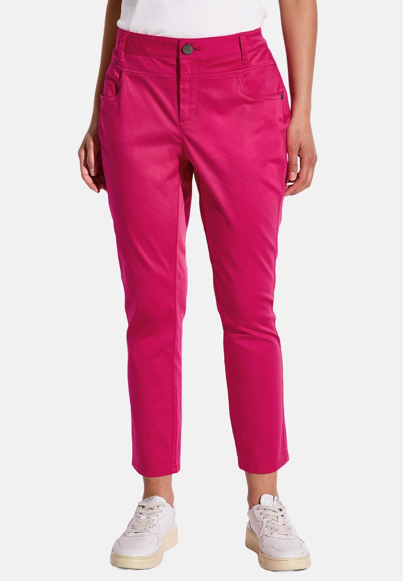 Pantalons en coton mélangé rose avec une coupe slim, dotés d'une fermeture à bouton, d passants de ceinture et de poches avant. Portés avec des baskets blanches.